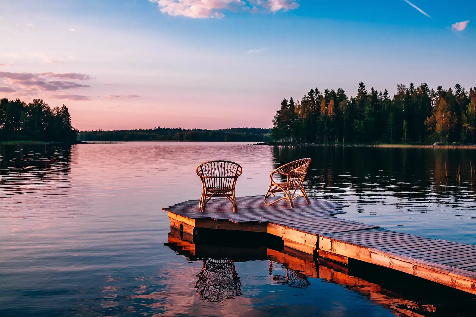 Lakefront land at sunset with chairs on the dock